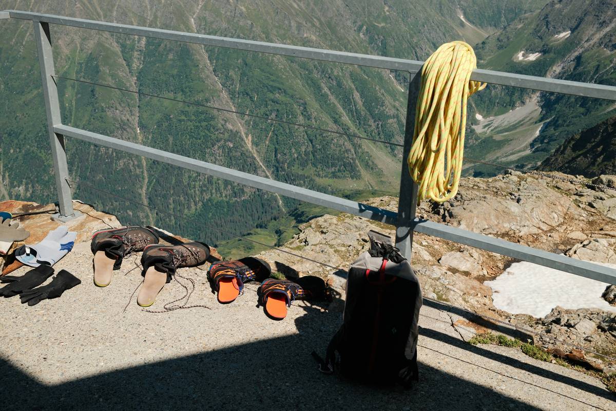 Climber placing an ice piton for steep terrain with correct upward angle in alpine setting