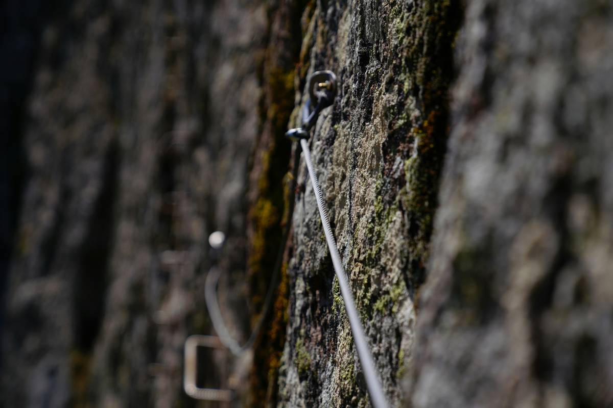 Climber placing a piton for aid soloing on a steep alpine wall